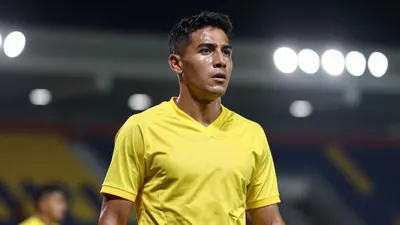 A mid-30s male Ecuadorian player in a solid yellow jersey, waist-up, focused expression, background blurred stadium...