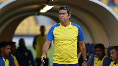 High-contrast image of a rugged, 40-year-old Ecuador national team coach, standing in the Estadio Rodrigo Paz Delgado...