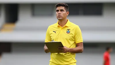 Photorealistic shot of a 28-35 year old Ecuador national team coach, athletic build, wearing a solid yellow polo shirt...