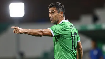 A photorealistic image of a 35-40 year old Argentine coach with a strong build, wearing a green jersey with a white...