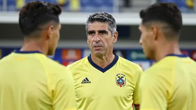A photograph of Sebastián Beccacece, the coach of the Ecuador national team, speaking with a player during a press...